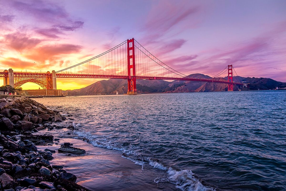 The Golden Gate Bridge at sunset under a pink and purple sky